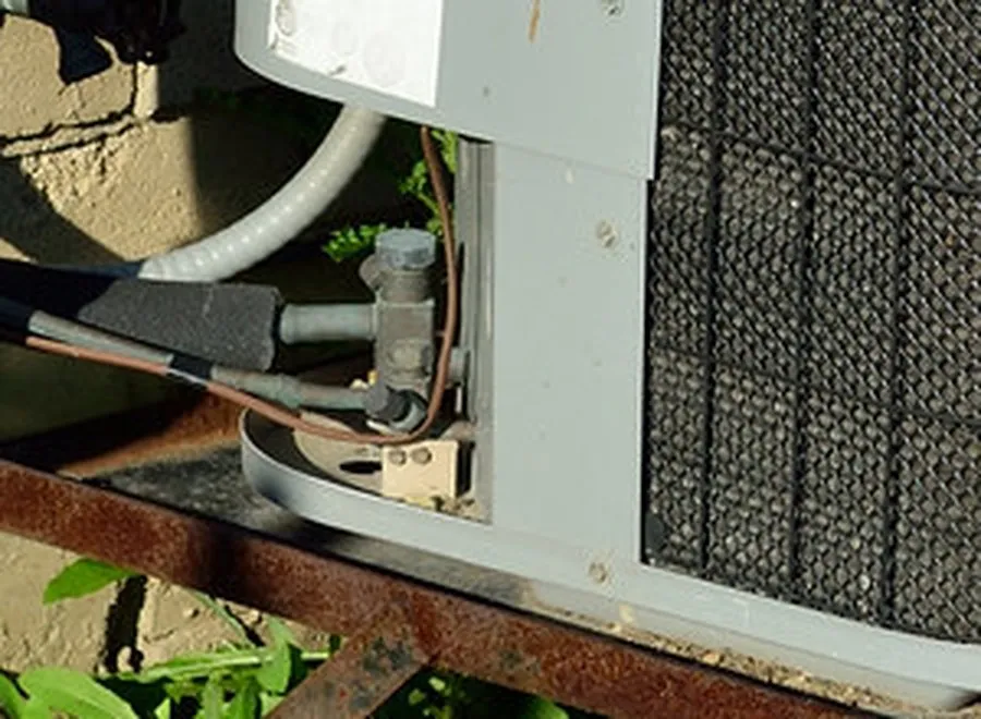Insulated refrigerant line and valves at the lower corner of an outdoor air conditioner
