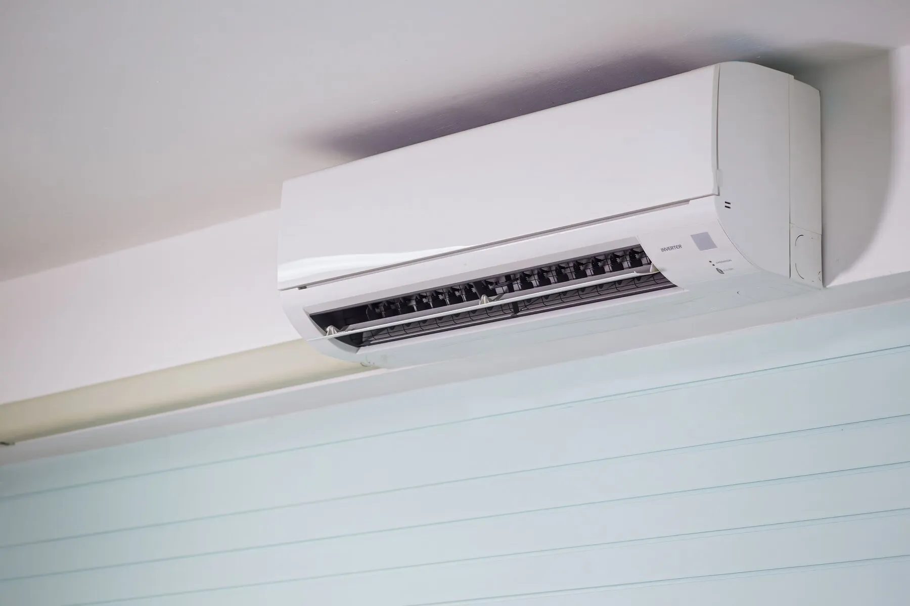 White ductless mini split indoor unit mounted high on an interior wall near the ceiling