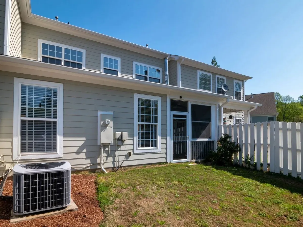 A two-storey house with an outdoor air conditioning unit in the side yard.
