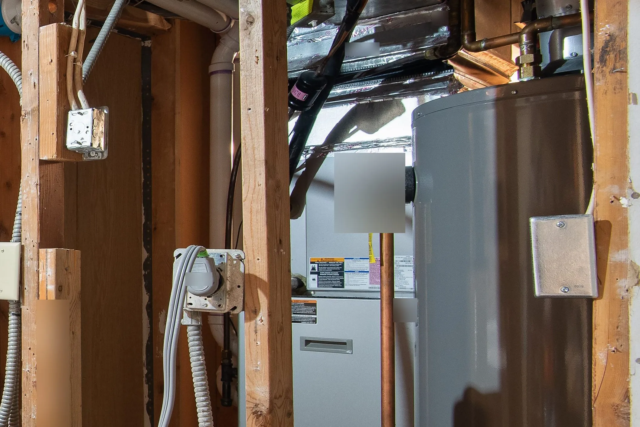 A high-efficiency gas furnace beside a water heater in an unfinished basement, with ductwork and refrigerant lines above