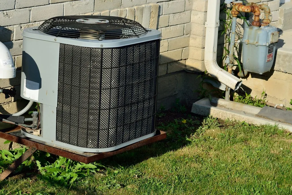 Outdoor central air conditioner condenser beside a house