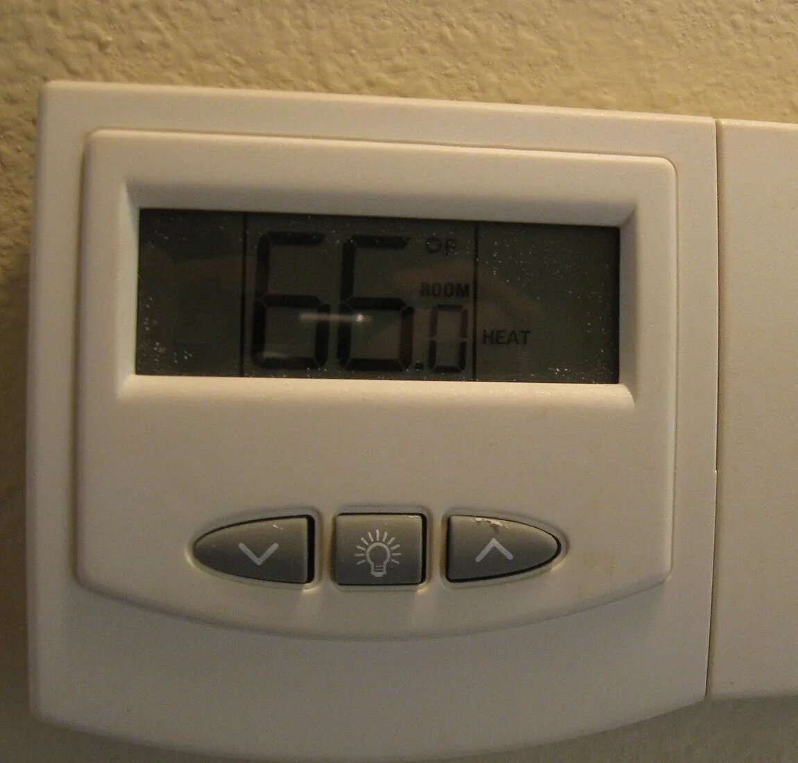 Wall thermostat display reading 66 degrees in heat mode
