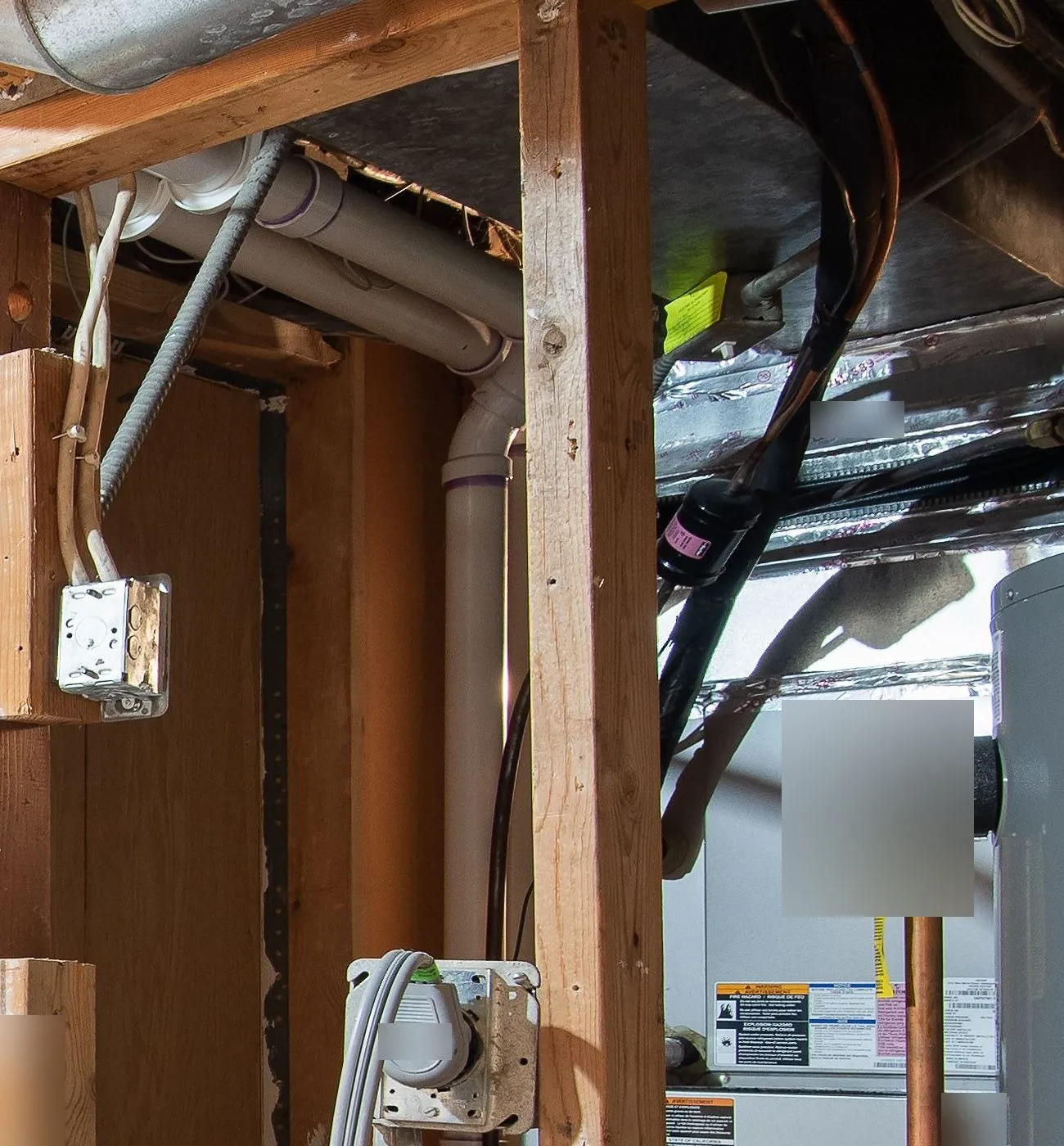 White plastic vent pipes running from a high-efficiency gas furnace along a basement ceiling
